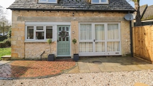 A two-story stone house with a green door, white-framed windows, and a brick pathway leading to the entrance. - Paddock View (Cheltenham)