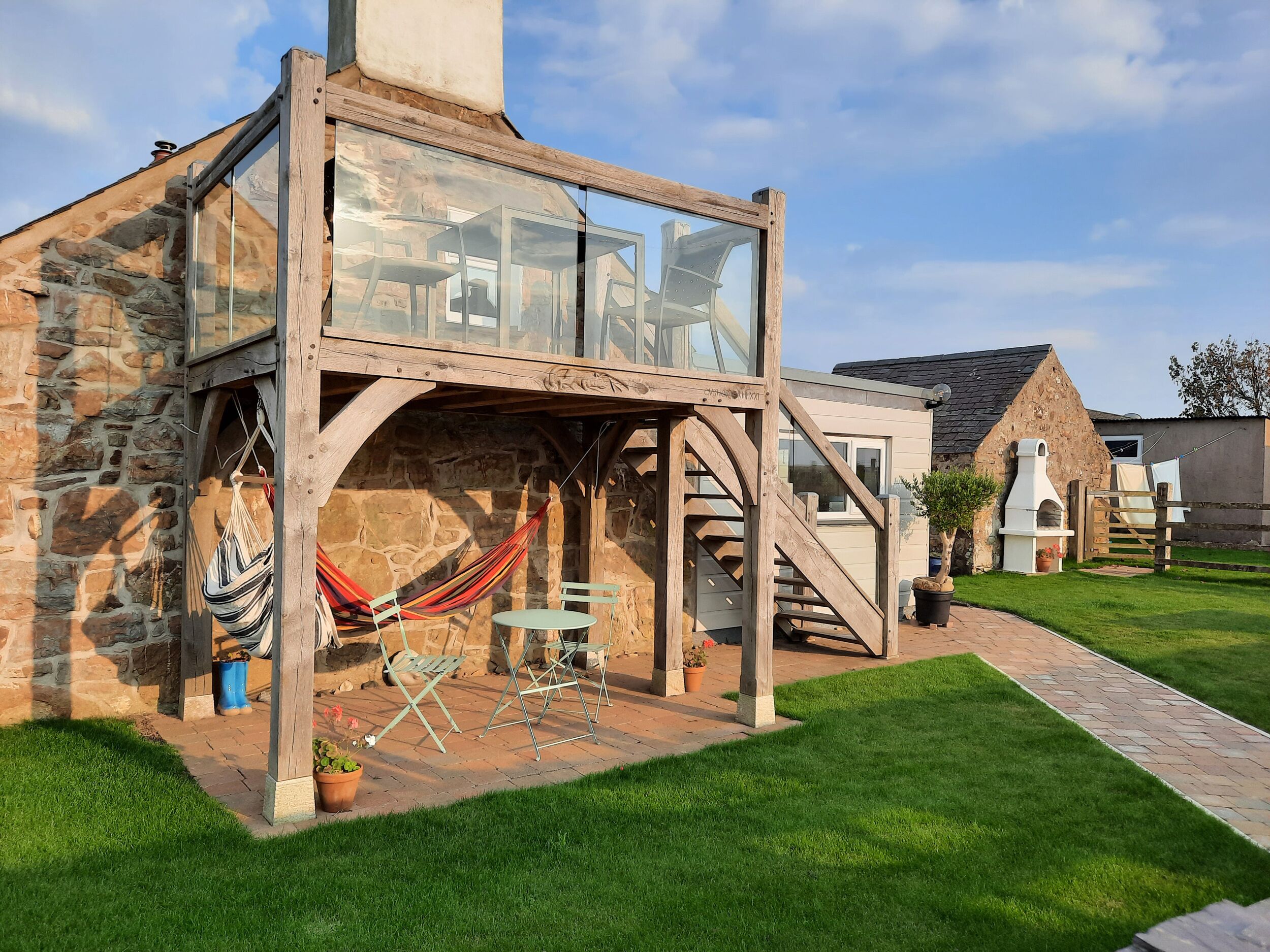 A rustic stone building with a glass enclosure, a hammock, and outdoor seating.