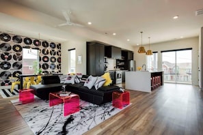 Ein moderner Wohnraum mit einer schwarzen Couch, roten Akzentstühlen und einer Wand voller Schallplatten.