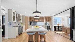 A modern kitchen with a central island, bar stools, and a pendant light. - C’est La Vie Beach Villa (Saint Helena Bay)
