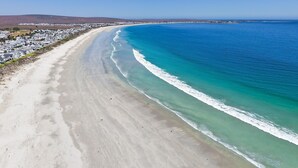 An aerial view of a coastal area with a wide sandy beach and a clear blue ocean. - C’est La Vie Beach Villa (Saint Helena Bay)