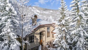A snow-covered house with a stone staircase leading to the entrance, surrounded by snow-laden trees. - Greystone 60 Five Bedroom (Beaver Creek)