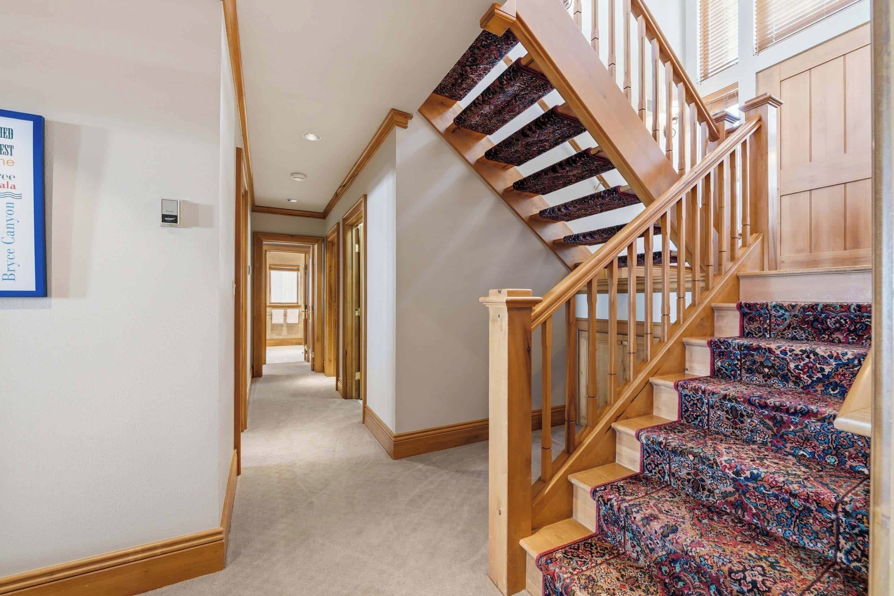 A hallway with carpeted stairs leading to a door.