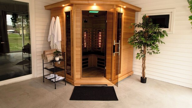 En sauna med træfacade, glasdøre og en sort måtte ved indgangen.