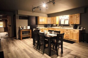 A modern kitchen with wooden cabinets, a dining table with chairs, and a built-in microwave.