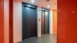 A modern elevator area with four elevators, each marked with a number. - Modern Flat with Balcony & Garage by HostWise (Porto)