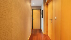 A hallway with wooden flooring and walls, leading to a door with a black frame. - Modern Flat with Balcony & Garage by HostWise (Porto)