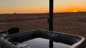 Un bain à remous installé à l’extérieur, offrant une vue sur le coucher de soleil.