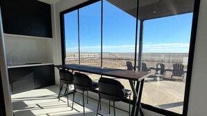Une cuisine moderne dotée d’une grande fenêtre, d’une table à manger avec des chaises, et offrant une vue sur la plage.