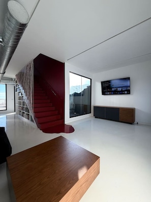 Un interior moderno con una escalera, un televisor de pantalla plana y un diseño minimalista.