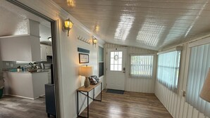 A hallway with wooden flooring, a kitchen area on the left, and a door with a window on the right. - Serenity House for Two! (Kissimmee)