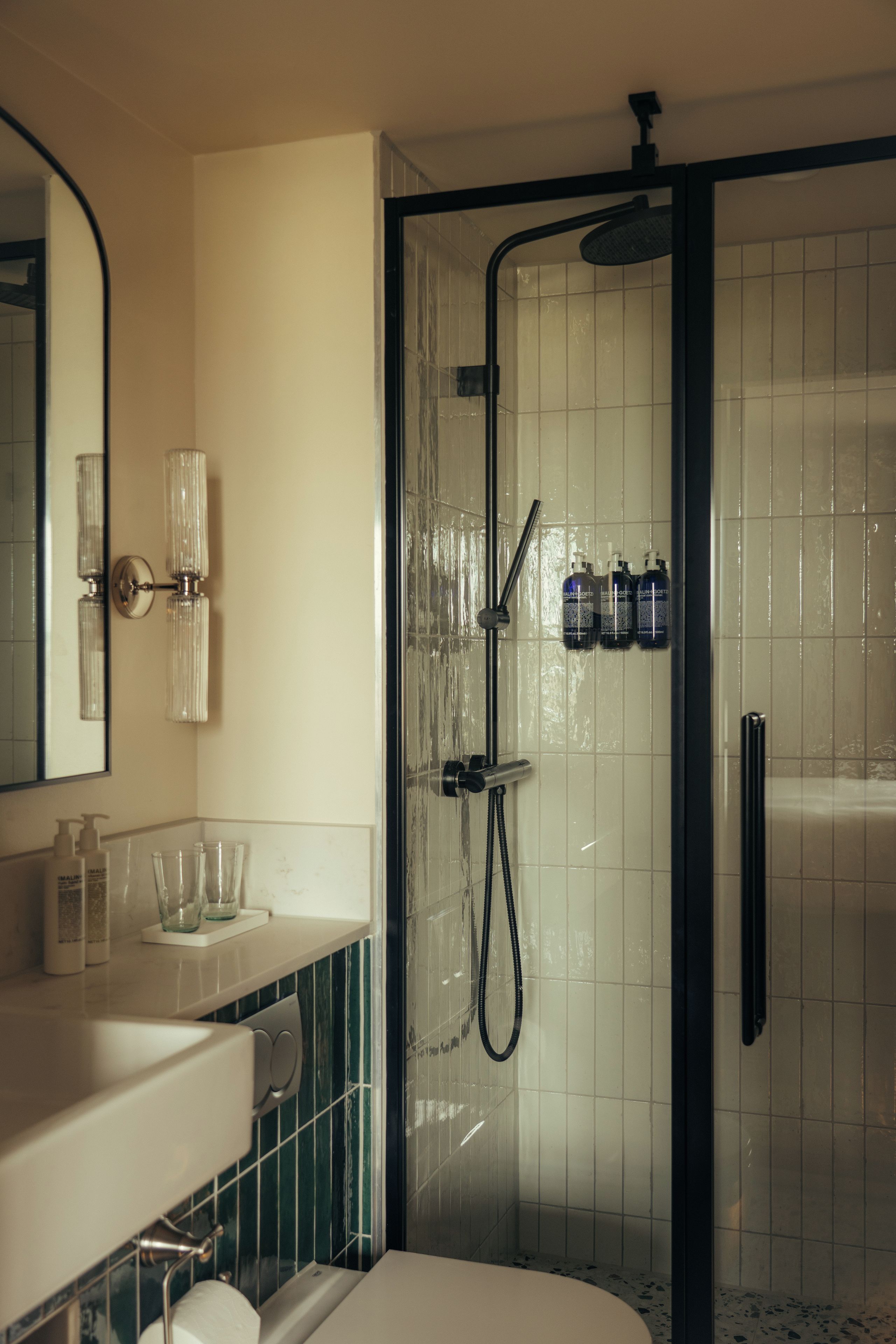 A bathroom with a glass-enclosed shower, a white sink, and a mirror.