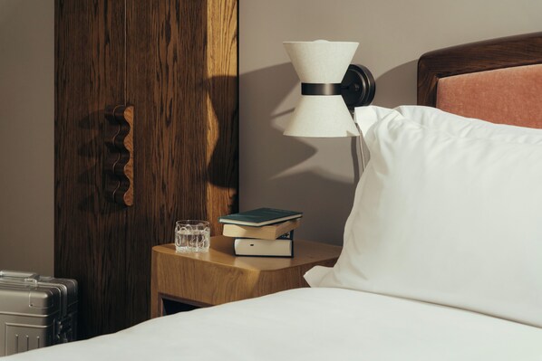 A neatly made bed with a pillow, a bedside table with a lamp, a book, and a glass of water. - The Webster Covent Garden – New Lifestyle Hotel – £60 Food & Drink Credit per Stay (London)