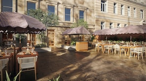 An outdoor dining area with tables and chairs, striped umbrellas, and a building in the background. - The Webster Covent Garden – New Lifestyle Hotel – £60 Food & Drink Credit per Stay (London)
