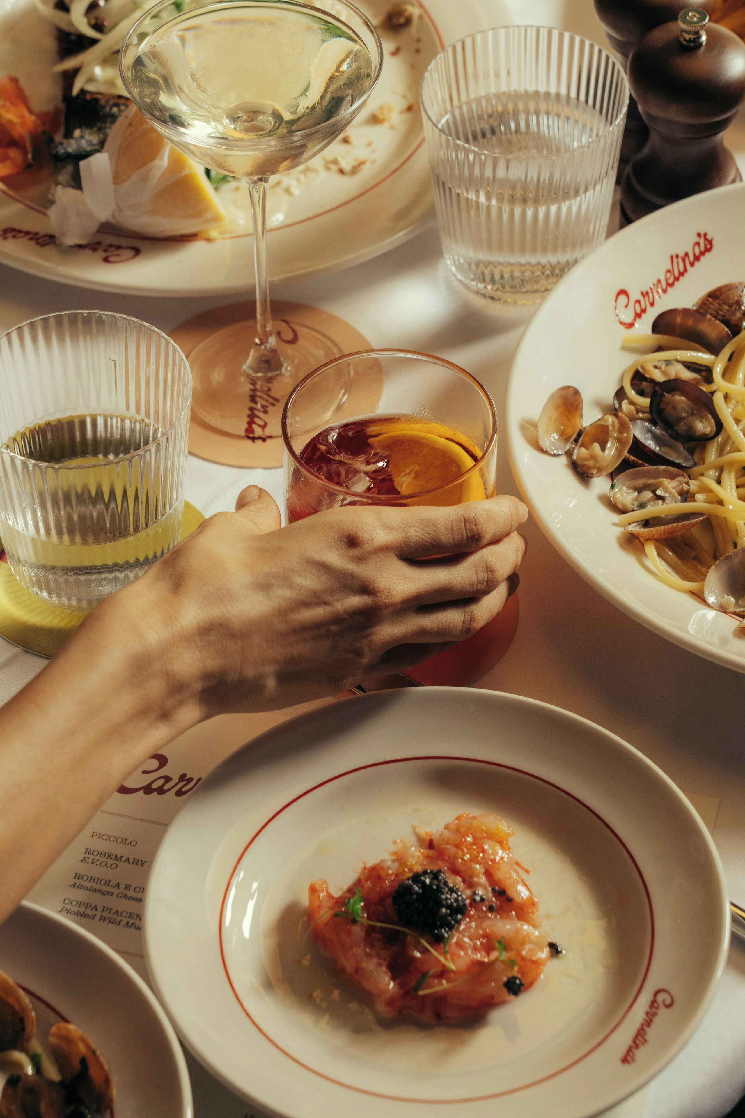Una mesa de comedor con platos de comida, vasos y una carta.