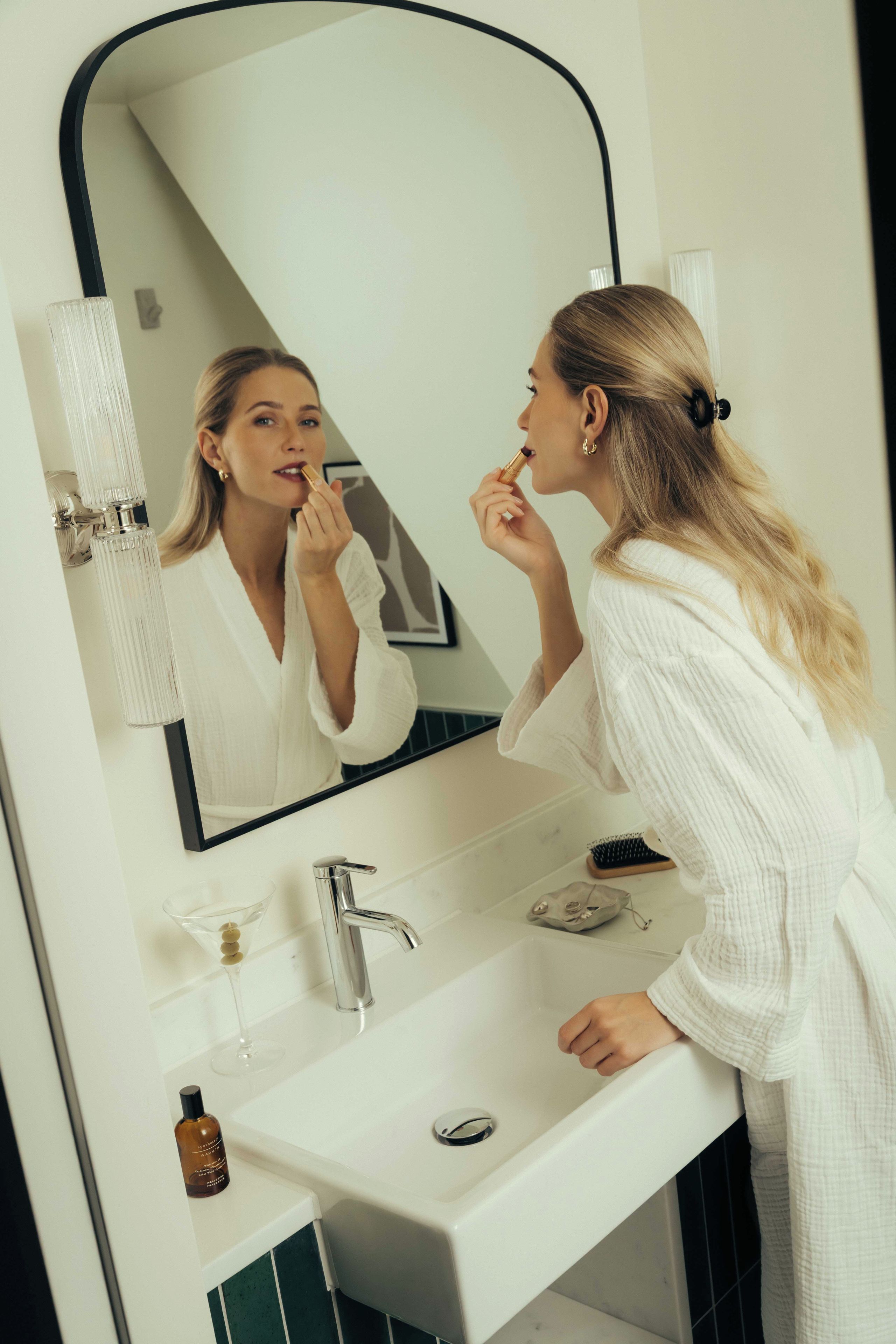 A bathroom with a white sink, a mirror, a faucet, and a bottle of liquid soap.