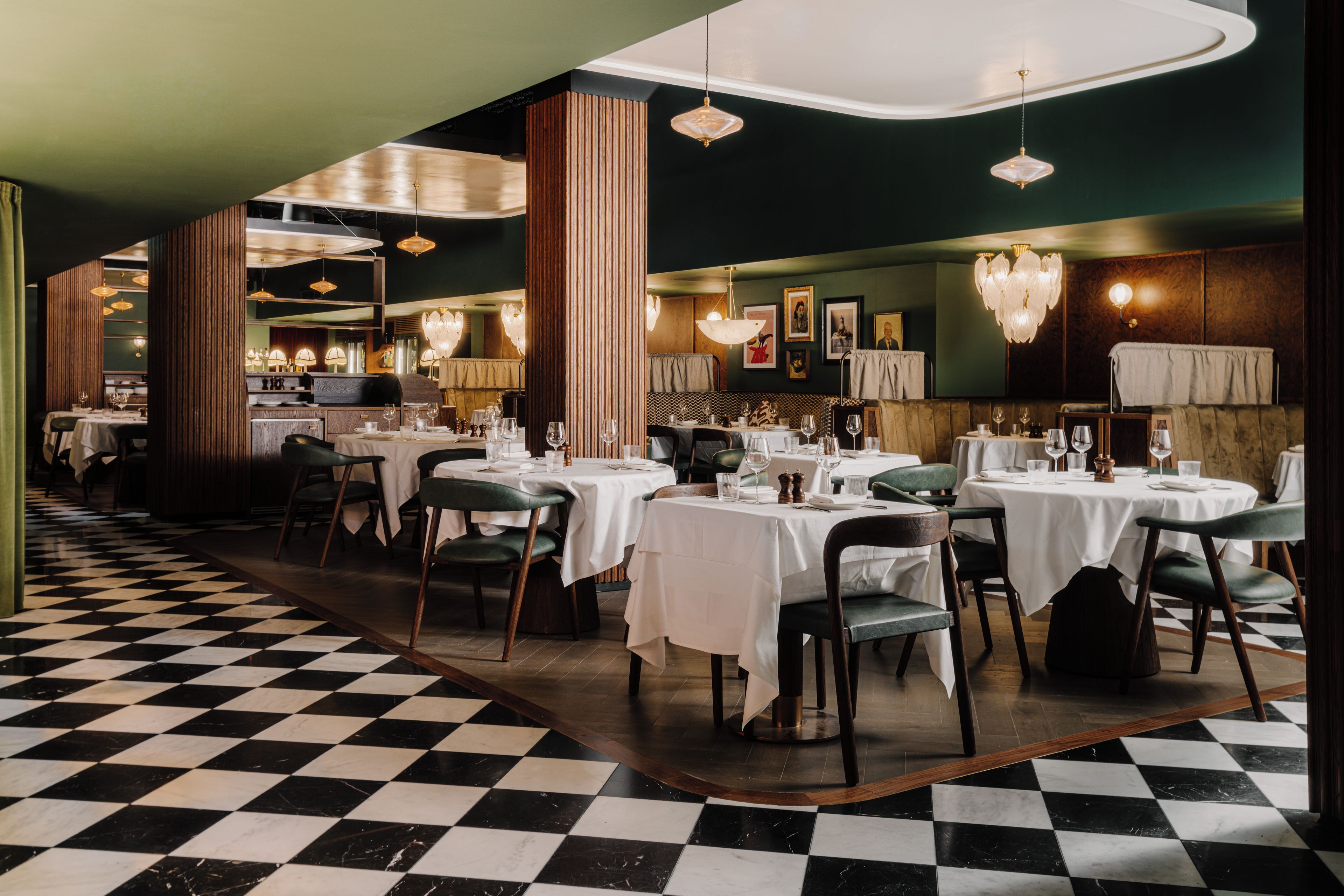 A restaurant with checkered flooring, round tables, and green chairs.