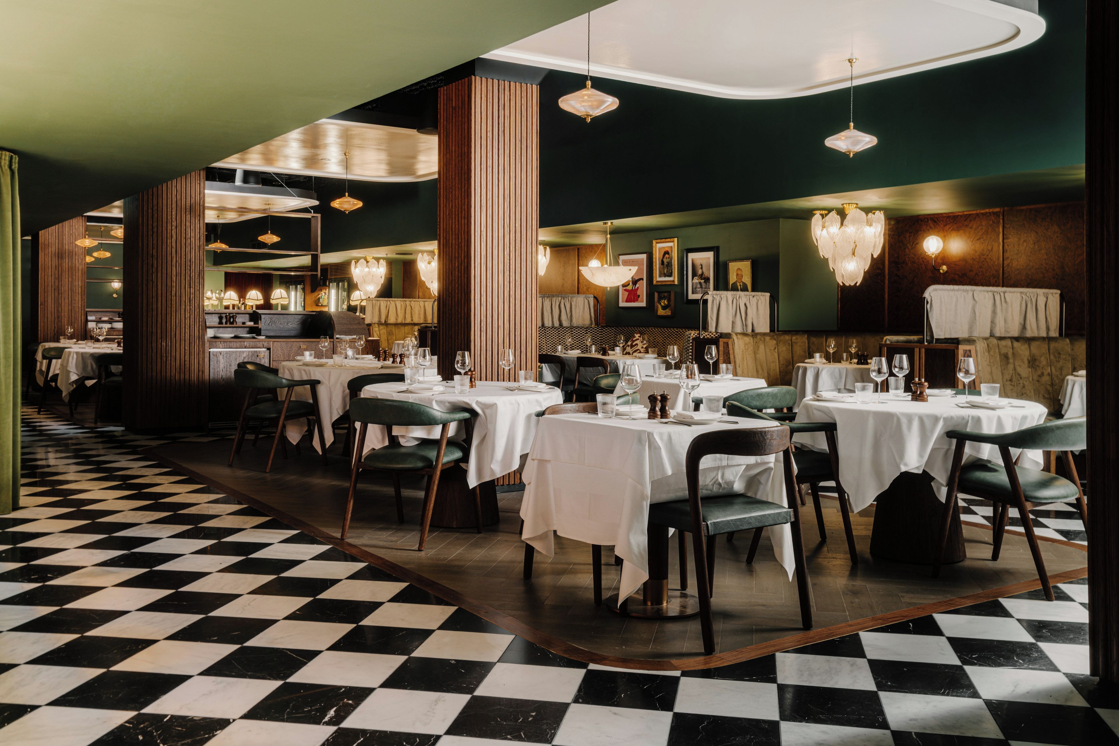 Un restaurant avec un sol à carreaux, des tables rondes et des chaises vertes.