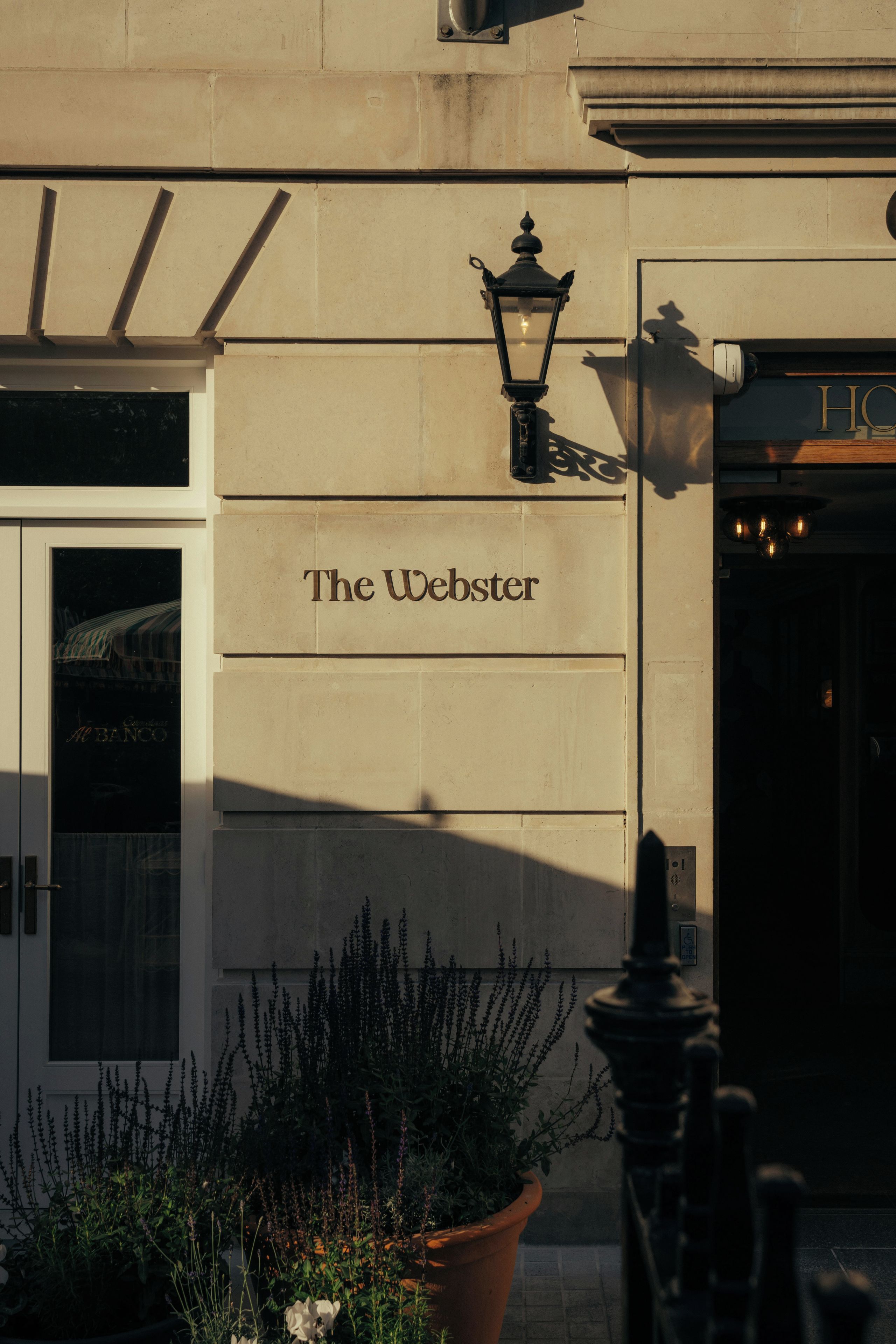 A building facade with a sign reading 'The Webster' and a traditional street lamp.