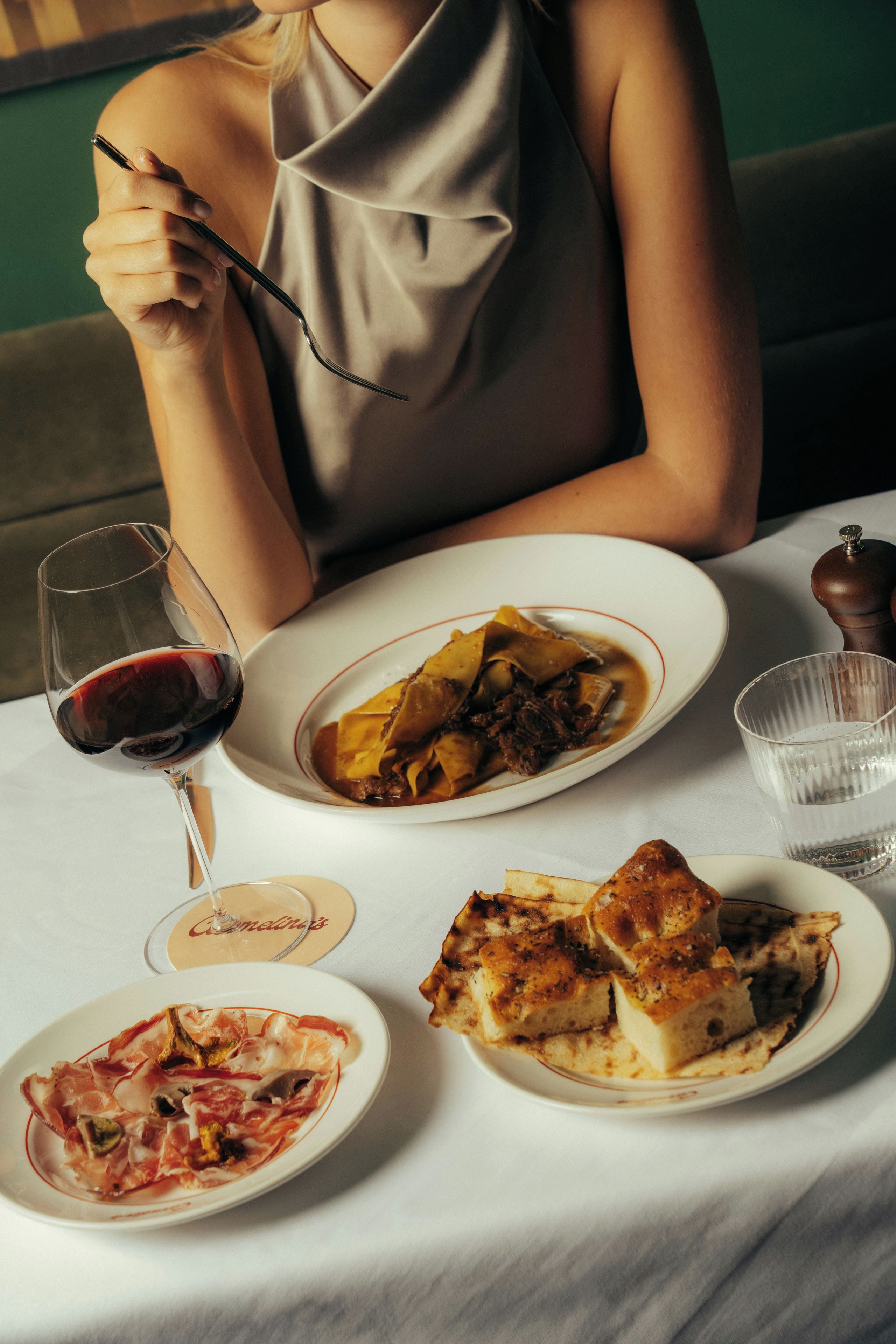 A dining table with plates of food, a glass of red wine, and a water glass.