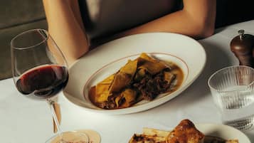 A dining table with plates of food, a glass of red wine, and a water glass.
