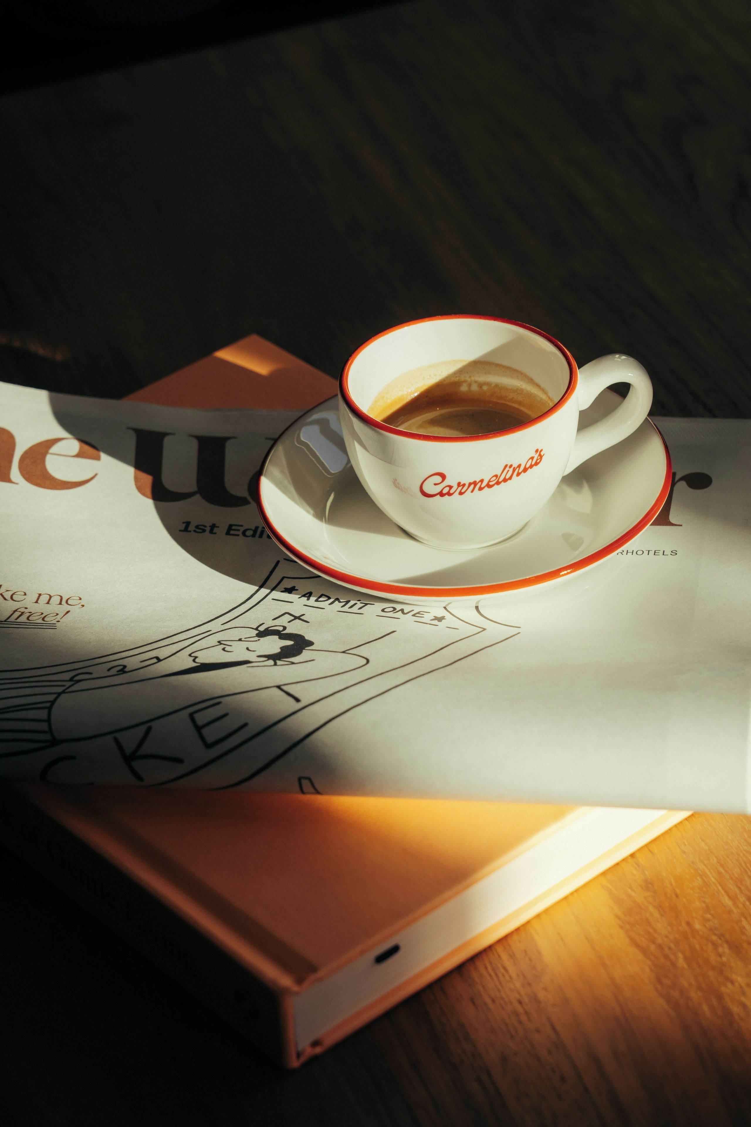 A cup of coffee on a saucer with a newspaper underneath.