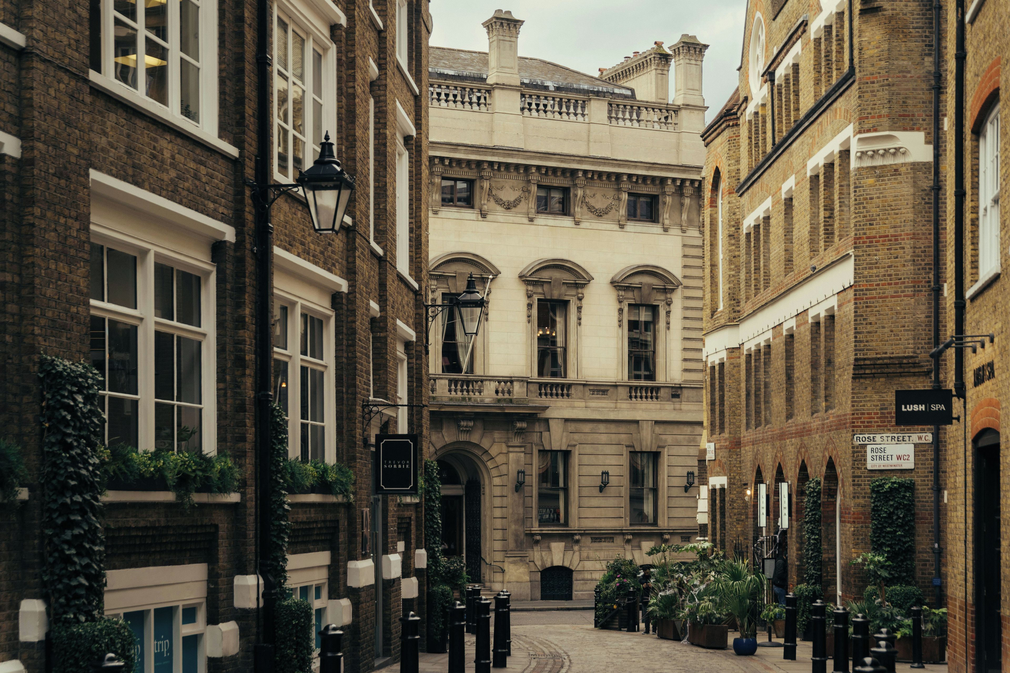 A narrow street with historic buildings, a sign for 'LUSH SPA,' and a 'ROSE STREET WC' sign.