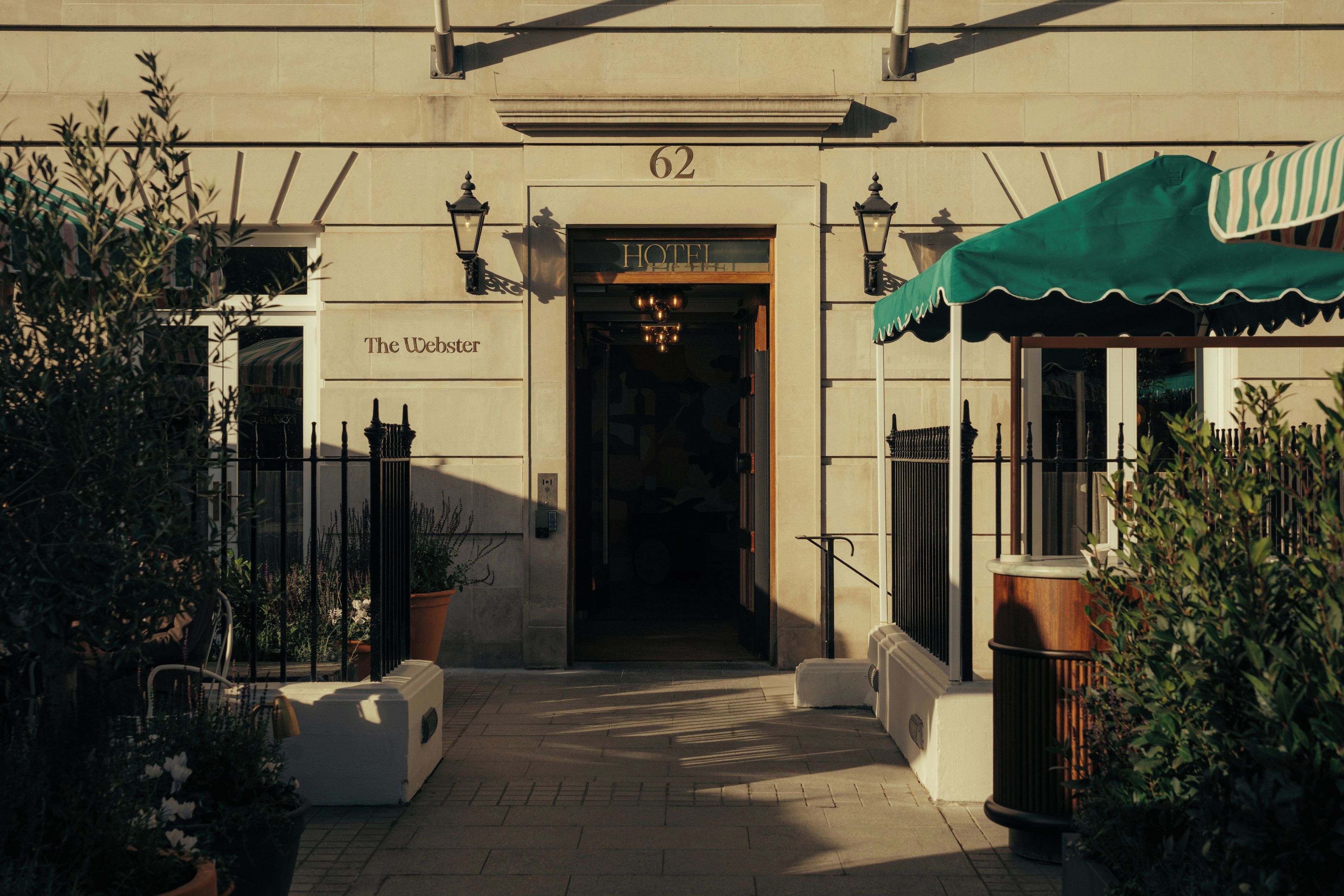 L’entrée d’un hôtel, avec une enseigne indiquant « The Webster » et le numéro « 62 » au-dessus.