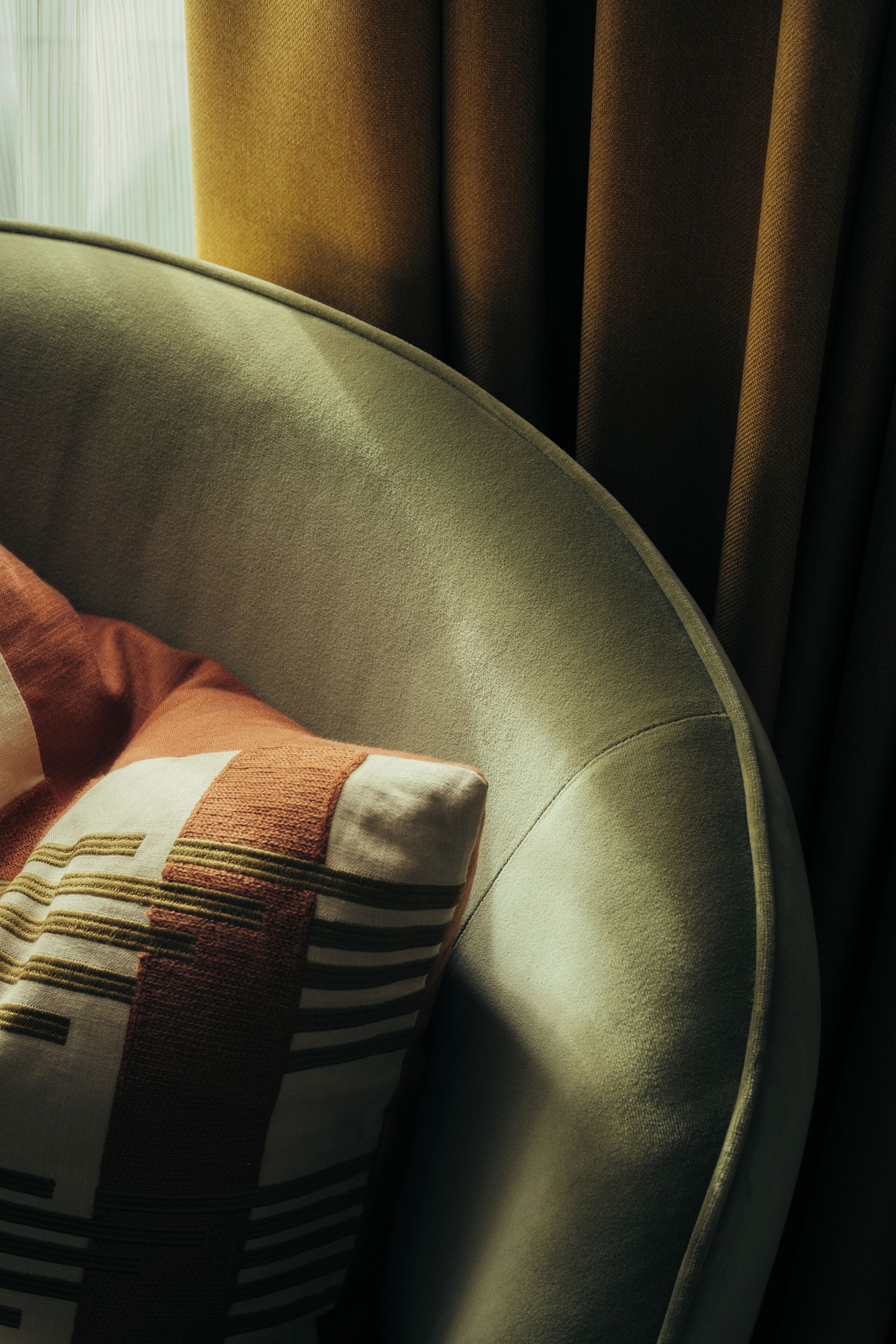 A curved chair with a striped pillow.