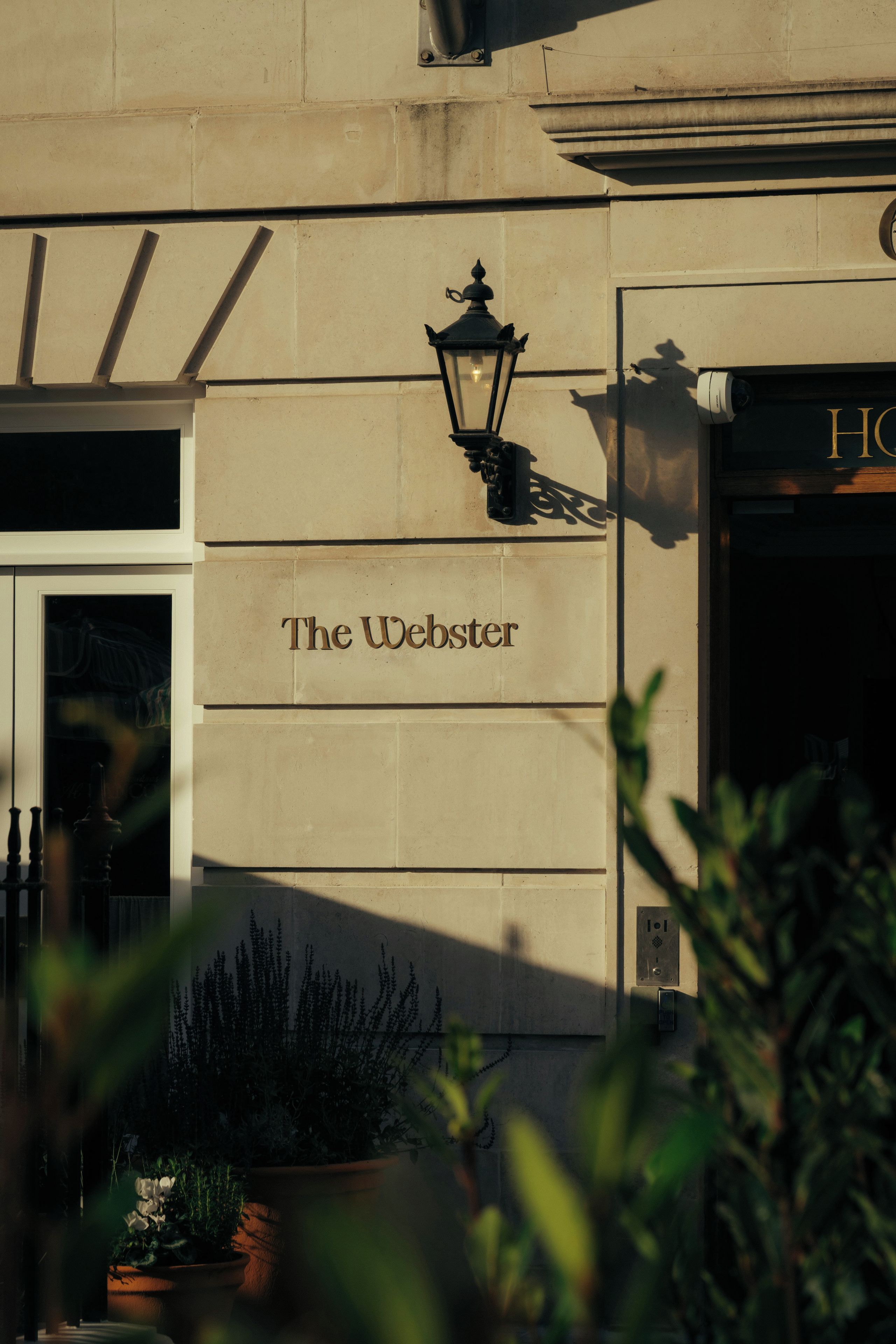 A building facade with a sign reading 'The Webster' and a black street lamp.
