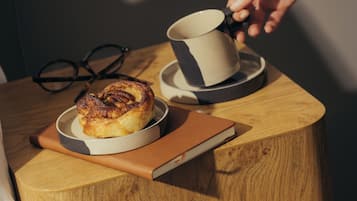 A wooden side table with a cup, a book, and a pastry.