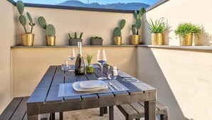 A wooden table set for dining with a view of cacti and a mountain in the background. - Penthouse with Private Terrace (Como)