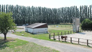 Una granja rural con un granero, un corral cercado y un árbol.