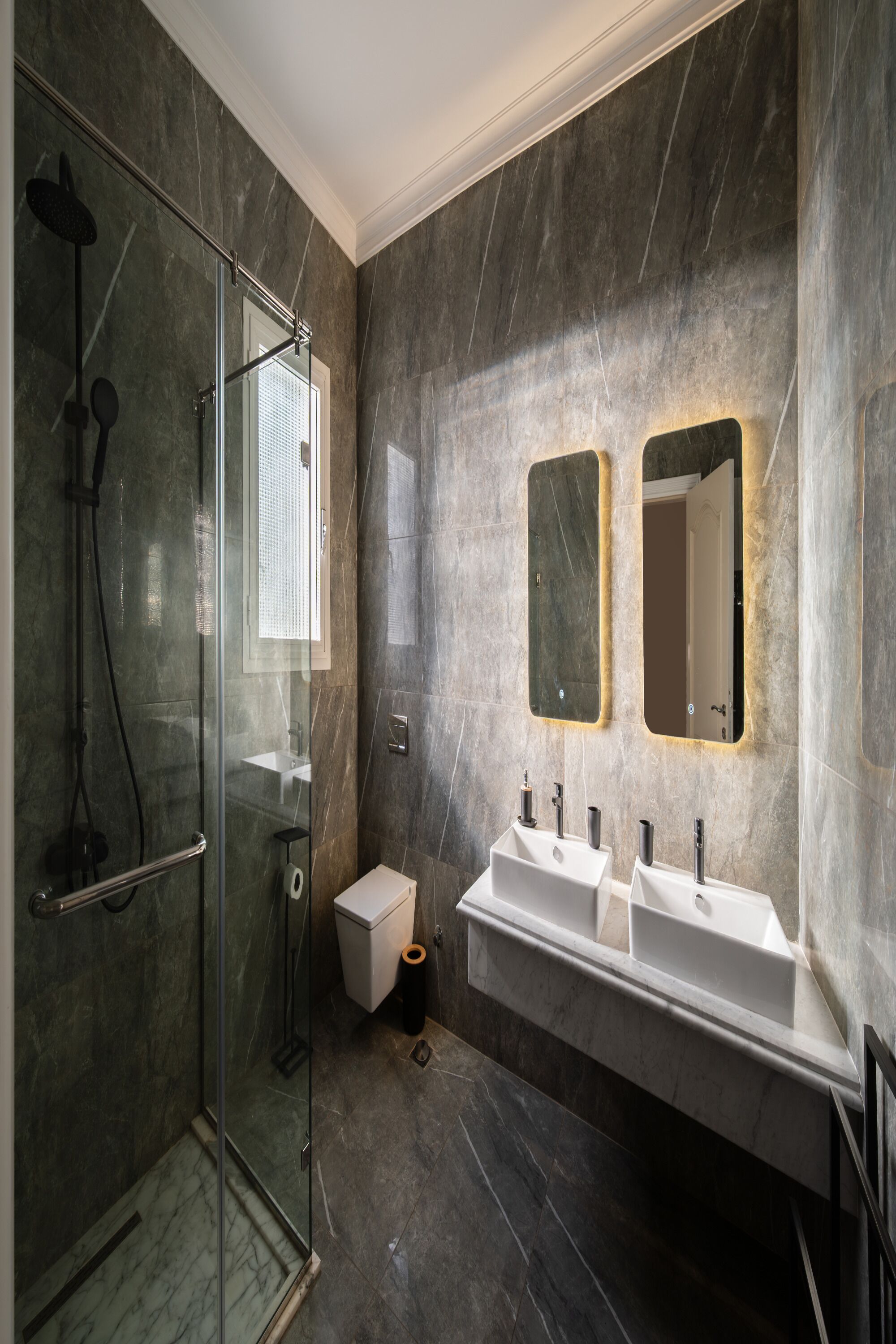 A modern bathroom with a glass-enclosed shower, two sinks, and two wall-mounted mirrors.