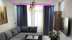 Ein modernes Wohnzimmer mit einem Ecksofa, einem Couchtisch und einem an der Wand montierten Fernseher.