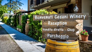 A wooden sign with directions to the reception, shop, and parking at Benvenuti Gesani Winery. - AGRITURISMO CESANI (San Gimignano)