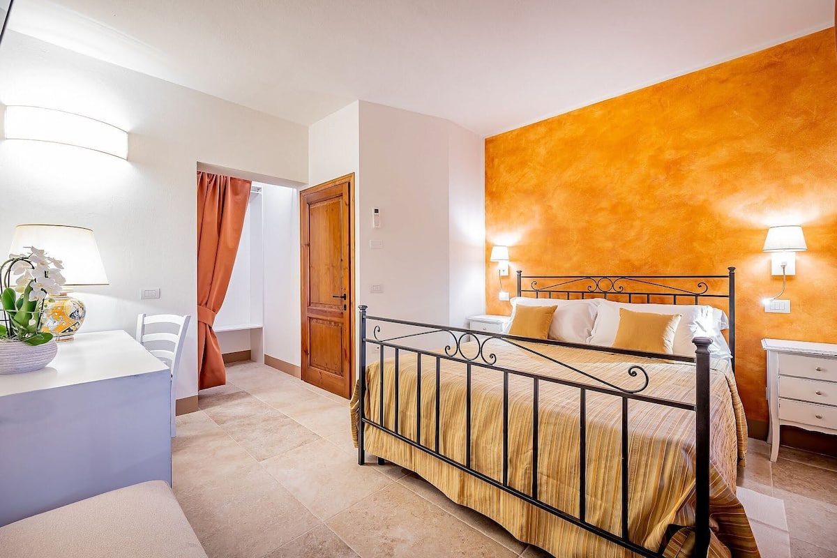 A hotel room with a bed, bedside tables, a desk, and a chair.