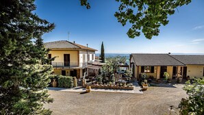 A courtyard with two buildings, a pergola, and potted plants. - AGRITURISMO CESANI (San Gimignano)