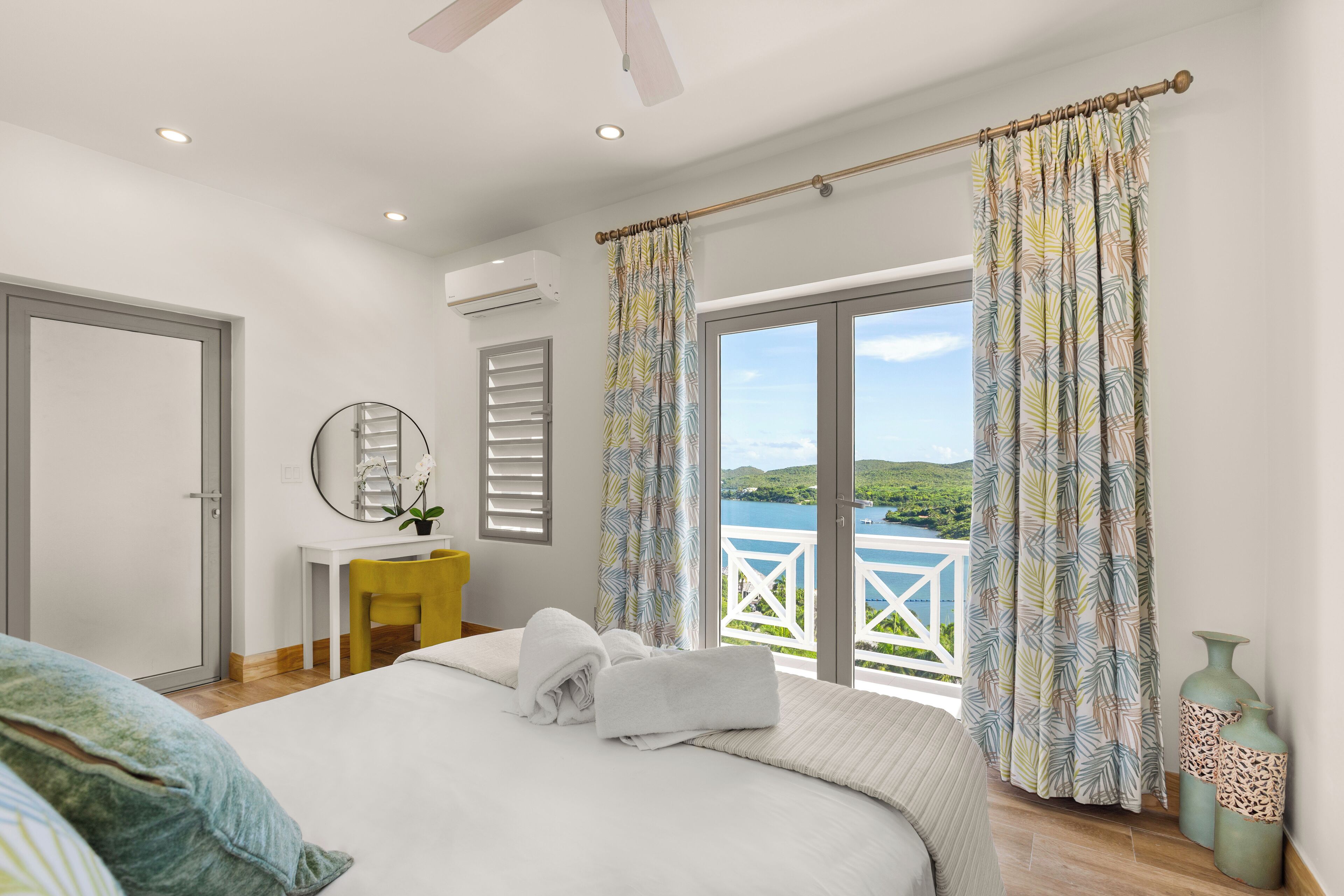 A bedroom with a bed, a desk, and a view of a lake.