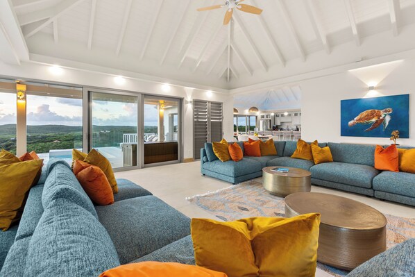 A spacious living area with a large blue sofa set, a coffee table, and a view of the outdoors.