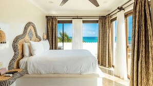 Une chambre avec un lit, un ventilateur de plafond et vue sur la plage.
