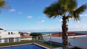 Ein Pool auf dem Dach mit freiem Blick auf das Meer, umgeben von weißen Gebäuden und einer Palme.