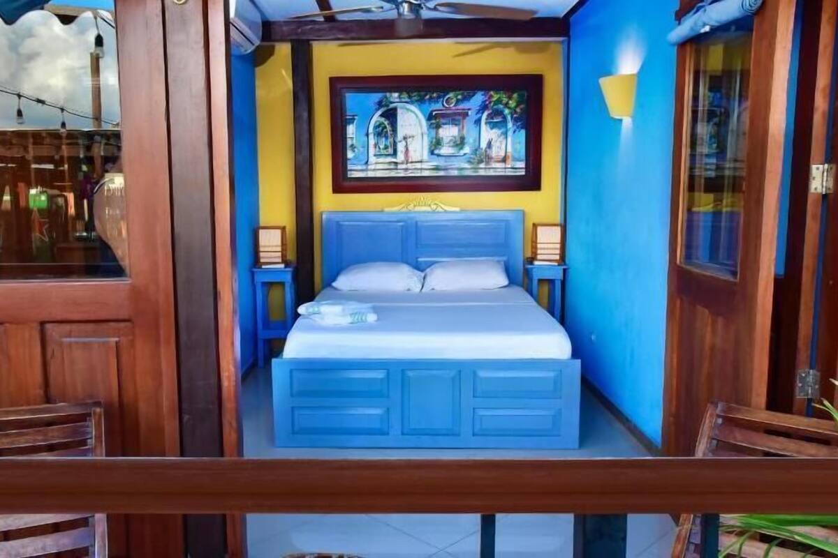 A room with a bed, a framed painting, and a window.