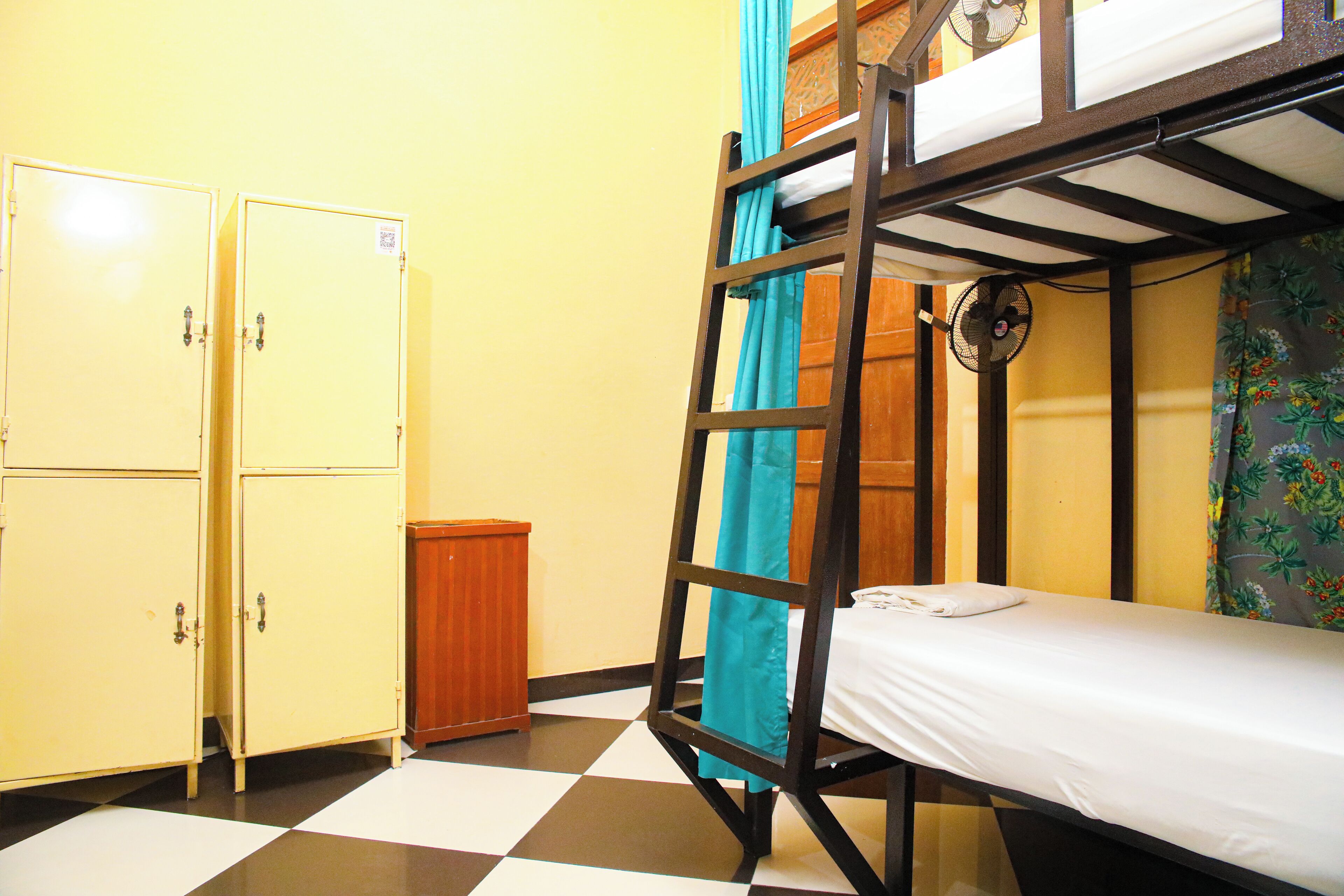 Un lit superposé avec un ventilateur, une armoire et un sol à carreaux.
