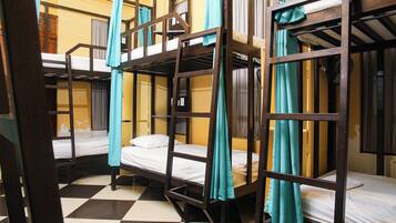A dormitory room with bunk beds, curtains, and a checkered floor.