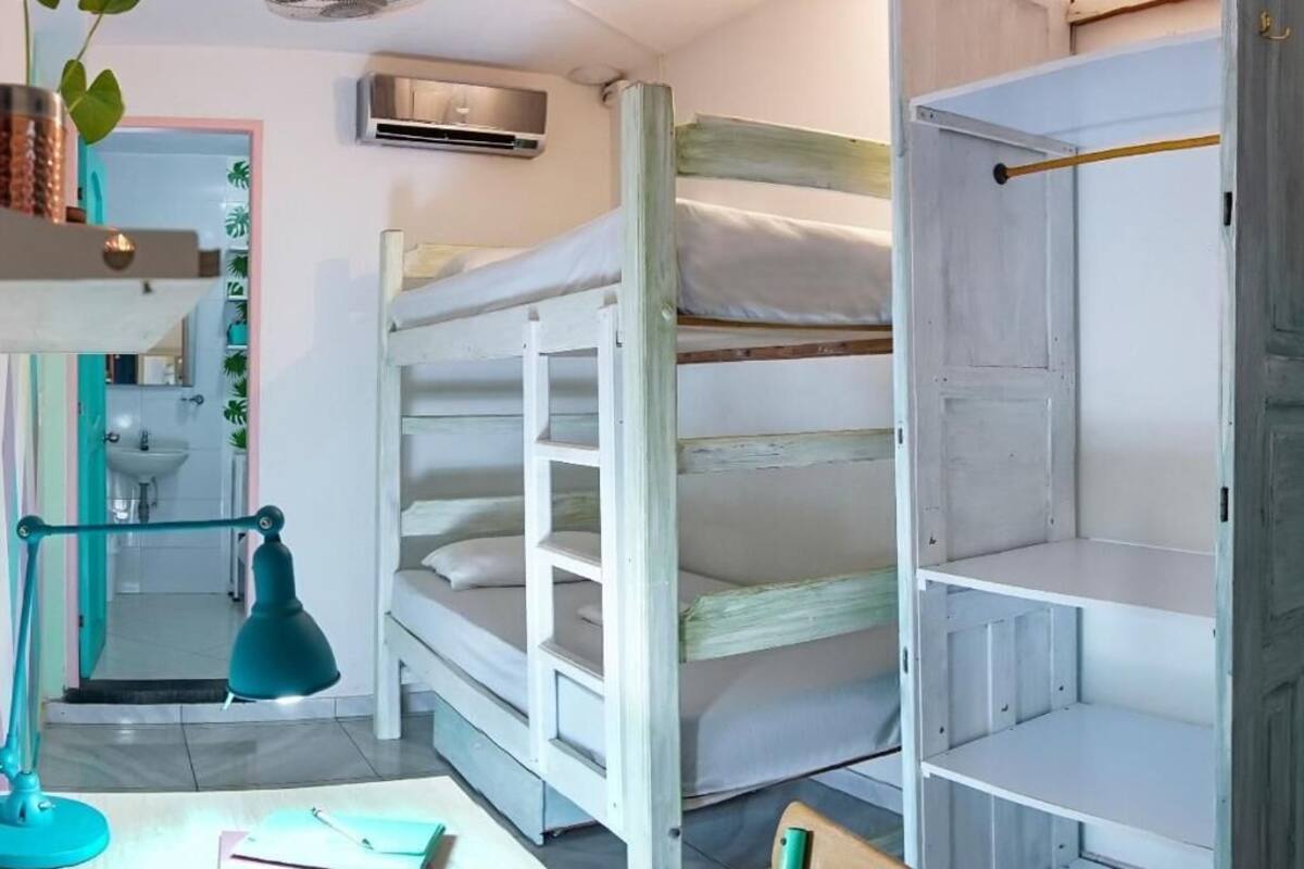A bunk bed room with a desk, a lamp, and a mirror.