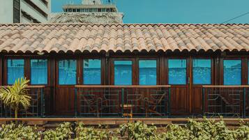 A building with a tiled roof, large windows, and a balcony with railings.