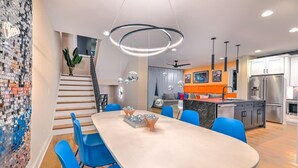 Uma cozinha moderna com uma ilha central, eletrodomésticos embutidos e um espaço de refeições com cadeiras azuis.