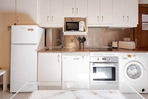 A compact kitchen with a microwave, oven, dishwasher, and washing machine. - Natural Light (Madrid)