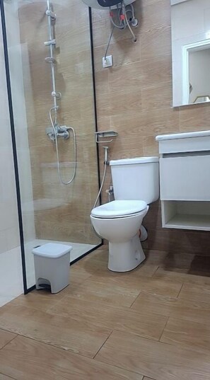 A modern bathroom with a glass shower enclosure, a white toilet, and a small white trash bin. - Apartment in Marina de Tanger with balcony (Tanger)